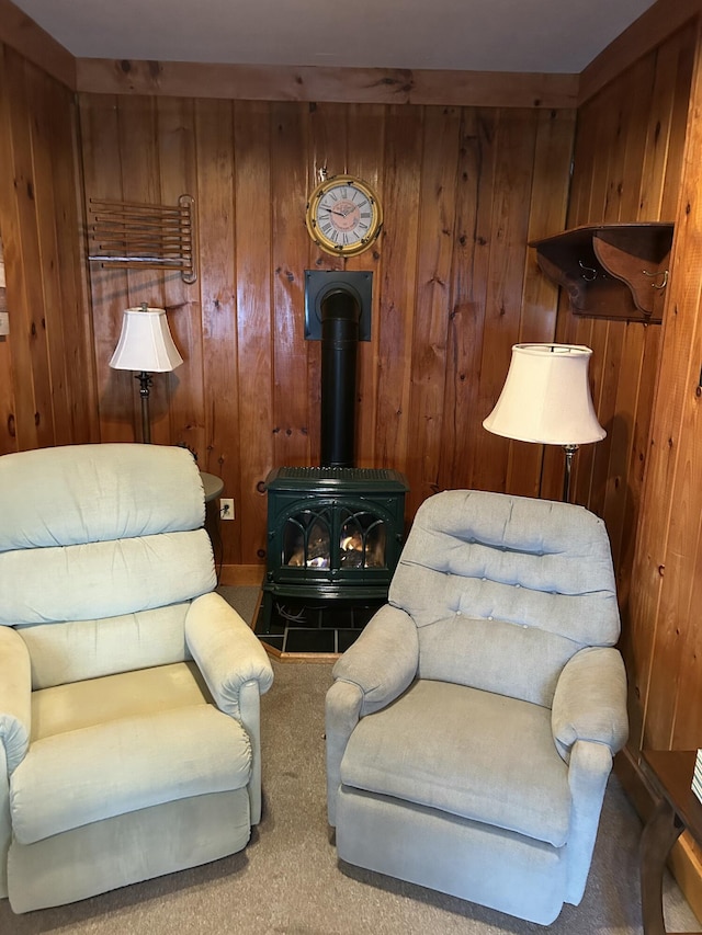 living area featuring carpet flooring, wooden walls, and a wood stove