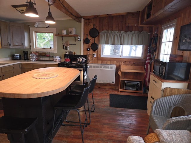 kitchen featuring radiator, black microwave, butcher block countertops, stainless steel gas range oven, and dark wood-type flooring