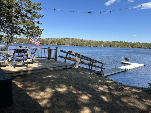 view of dock with a water view and a forest view