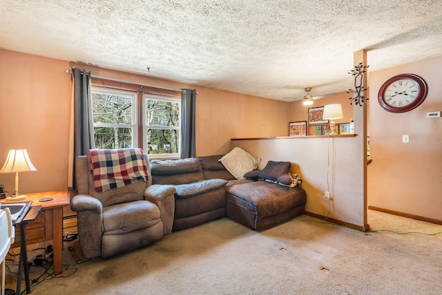 carpeted living area with a textured ceiling, ceiling fan, baseboards, and a desk