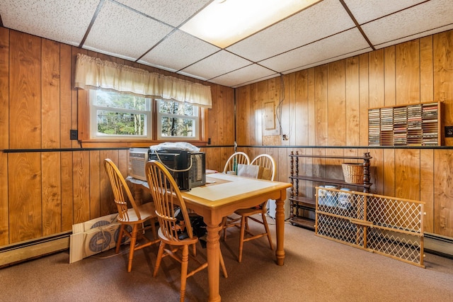 carpeted dining room with wooden walls and a paneled ceiling