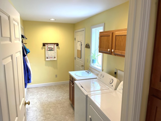 laundry area featuring independent washer and dryer, a sink, baseboards, cabinet space, and light floors