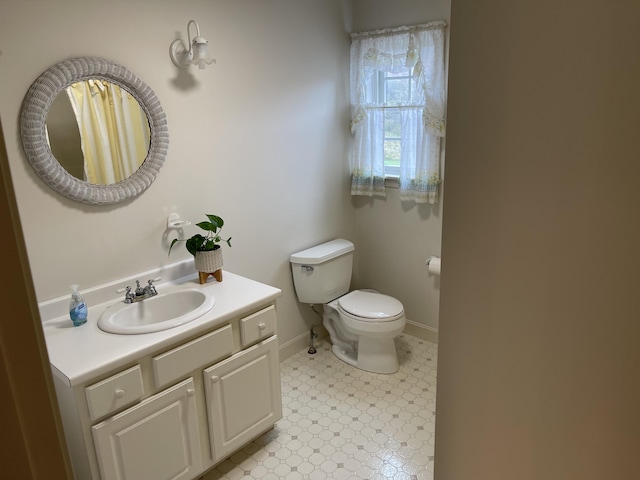 bathroom featuring toilet, vanity, and baseboards