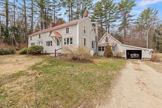 view of front facade with metal roof, a front lawn, driveway, and a chimney