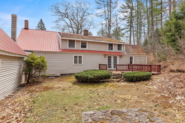 rear view of house featuring a deck, french doors, a chimney, and metal roof