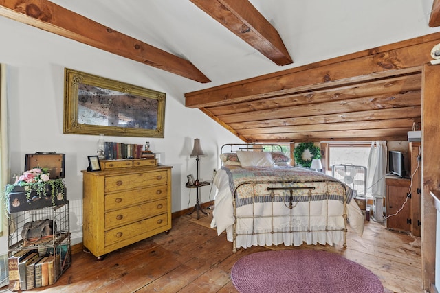bedroom featuring baseboards, lofted ceiling with beams, and wood-type flooring