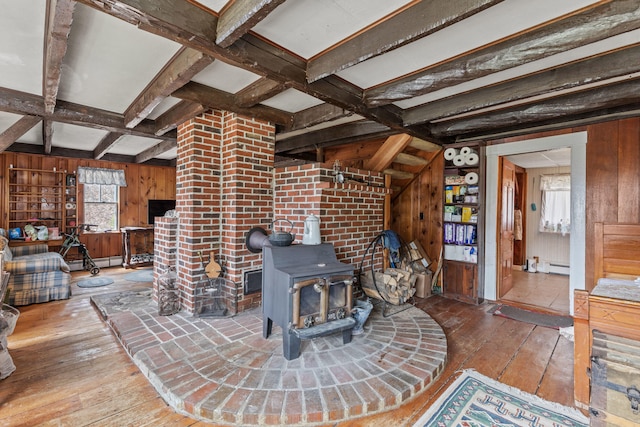 living area featuring coffered ceiling, beamed ceiling, wood walls, wood-type flooring, and a wood stove