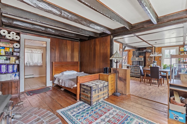 bedroom with hardwood / wood-style floors, baseboard heating, wood walls, and beam ceiling