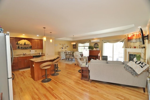 living room with a raised ceiling, a fireplace, a wall mounted air conditioner, light wood-style flooring, and recessed lighting