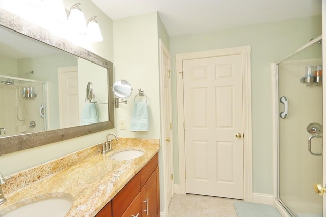 bathroom featuring a sink, tile patterned flooring, a shower with door, and double vanity