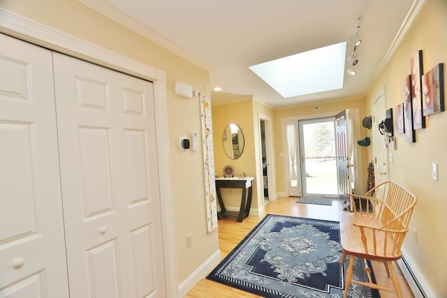 doorway to outside featuring crown molding, light wood-style floors, baseboards, a baseboard radiator, and a skylight