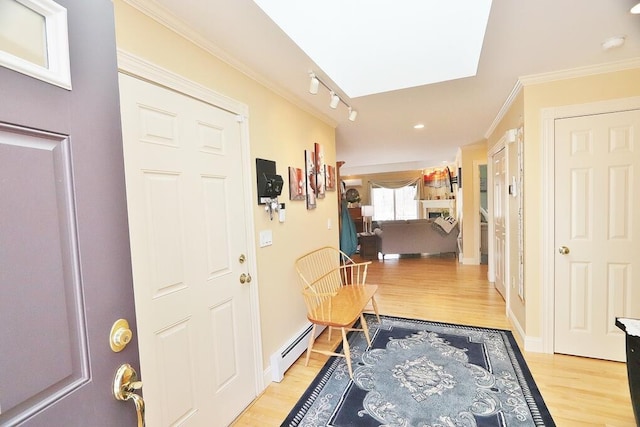 entryway with track lighting, ornamental molding, light wood finished floors, and baseboard heating