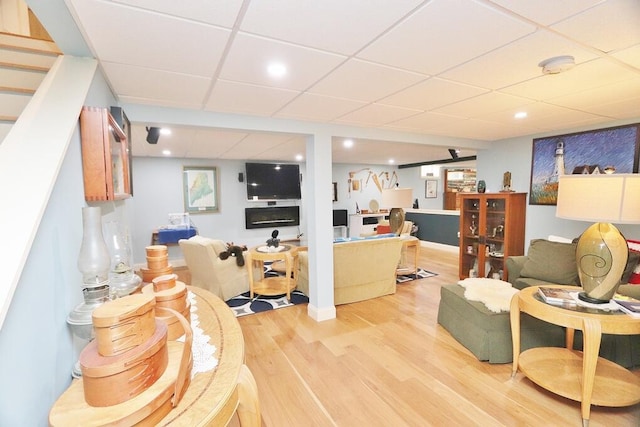 living room featuring light wood-type flooring and a paneled ceiling