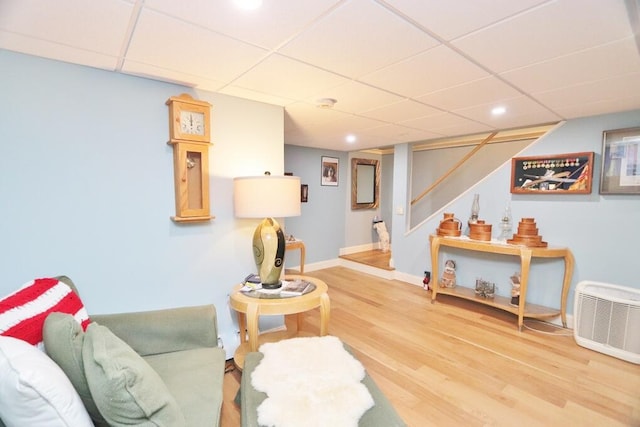 living area featuring recessed lighting, a paneled ceiling, wood finished floors, and stairway