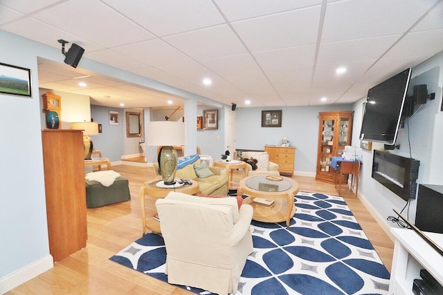 living area with recessed lighting, baseboards, a drop ceiling, and wood finished floors