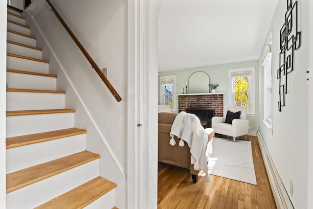 17 US Route 1, Falmouth, ME 04105 - stairway with hardwood / wood-style flooring, a baseboard heating unit, a brick fireplace, and baseboards