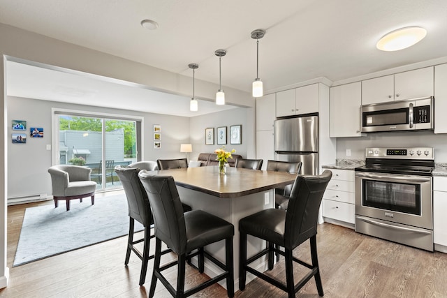 21 Valley St Unit 1, South Portland, ME 04106 - kitchen with stainless steel appliances, a baseboard heating unit, light wood-type flooring, and a breakfast bar