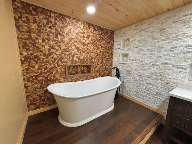 full bath with baseboards, wooden ceiling, a soaking tub, and vanity