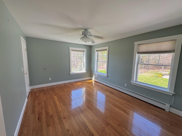 unfurnished room with baseboards, a ceiling fan, a baseboard heating unit, and wood finished floors