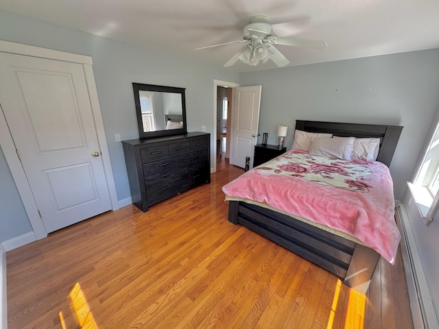bedroom with light wood-style floors, a baseboard radiator, baseboards, and ceiling fan