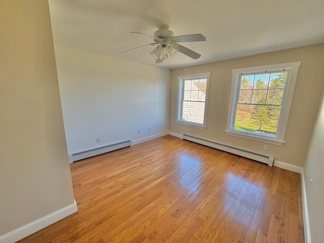 spare room with baseboards, a baseboard radiator, and light wood-type flooring