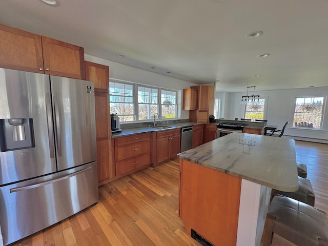 kitchen featuring a sink, brown cabinetry, stainless steel appliances, and light wood-type flooring