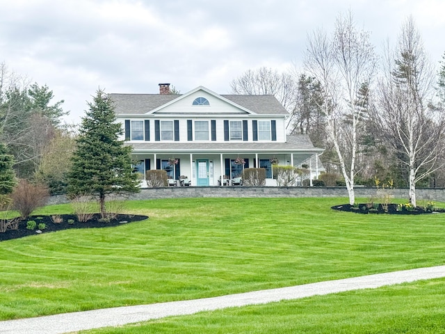 view of front of home with a shingled roof, a chimney, a porch, and a front yard