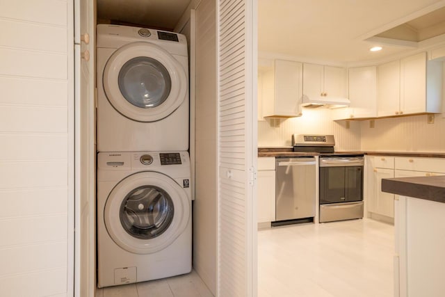 laundry area with stacked washing machine and dryer and recessed lighting