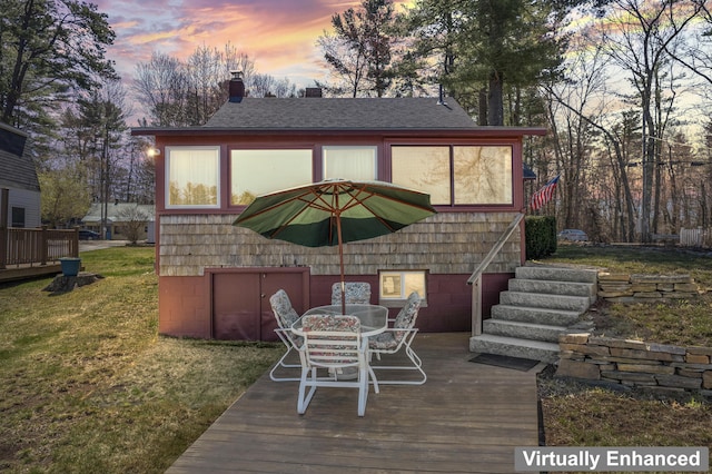wooden deck featuring a lawn and outdoor dining space
