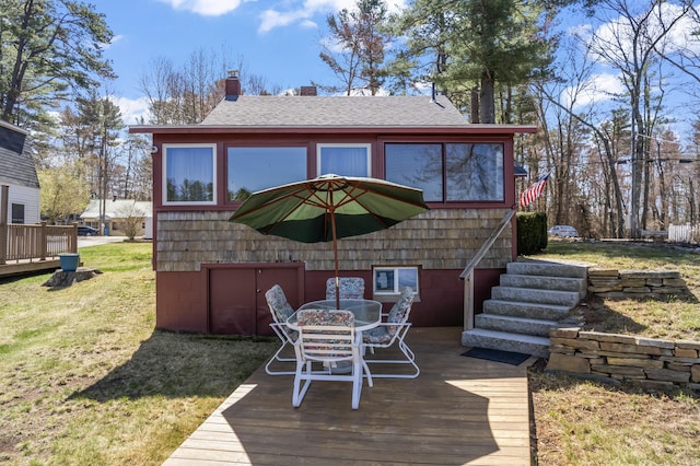 wooden terrace featuring a lawn and outdoor dining area