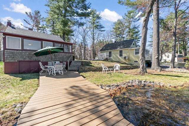 wooden deck with a yard, stairway, and outdoor dining space