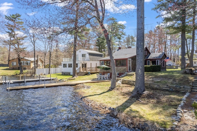 back of house featuring a lawn, fence, a chimney, and a deck with water view