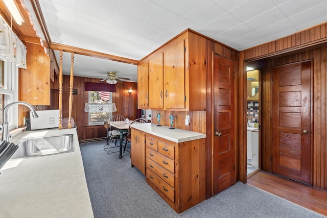 kitchen featuring a sink, carpet, wood walls, and light countertops