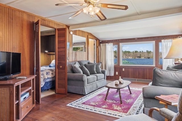living area featuring ceiling fan, wood finished floors, a baseboard radiator, lofted ceiling with beams, and wooden walls