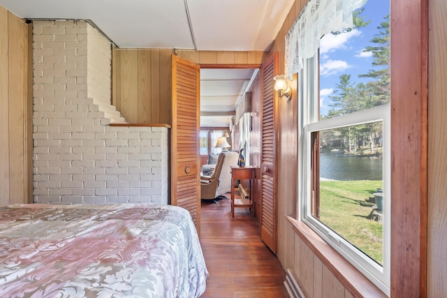 bedroom featuring wooden walls, a water view, and wood finished floors