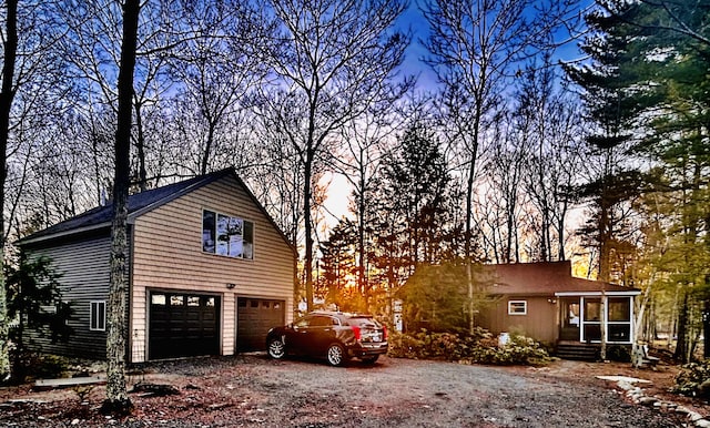 property exterior at dusk featuring a garage, a sunroom, and driveway