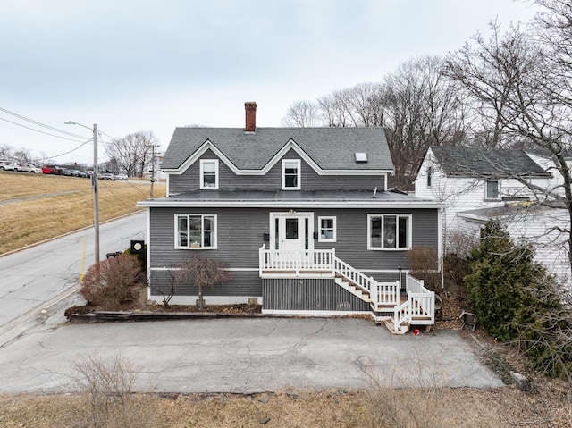 view of front of property featuring a shingled roof and a chimney