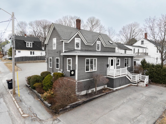 view of front of home featuring a shingled roof, fence, and a chimney