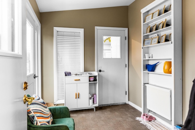 doorway to outside featuring baseboards, carpet flooring, and radiator heating unit