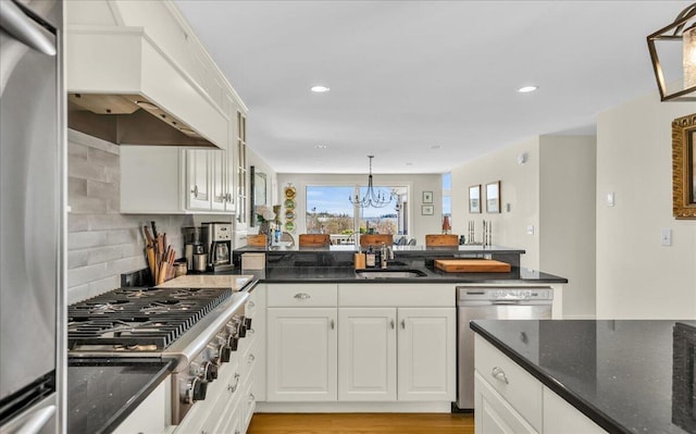 kitchen with a sink, appliances with stainless steel finishes, a peninsula, and white cabinetry