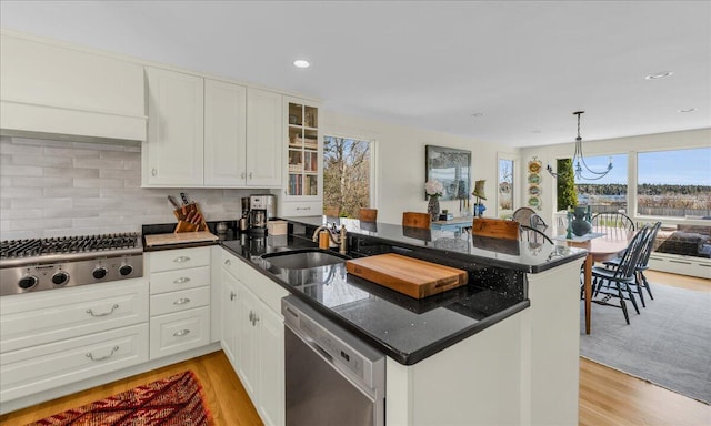 kitchen featuring a sink, light wood-style flooring, a peninsula, and stainless steel appliances