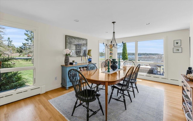 dining area with a chandelier, a baseboard heating unit, recessed lighting, and light wood finished floors