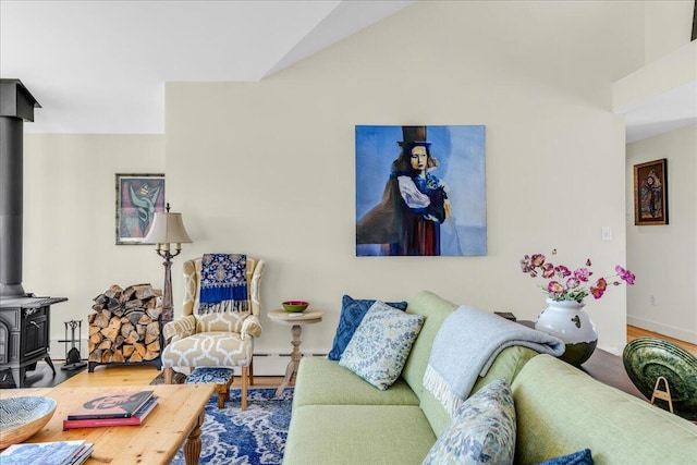 living room featuring a wood stove, wood finished floors, baseboards, baseboard heating, and vaulted ceiling
