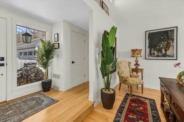sitting room featuring baseboards, radiator heating unit, and light wood-style flooring
