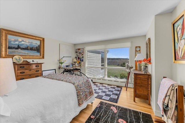 bedroom featuring a baseboard heating unit and light wood-type flooring