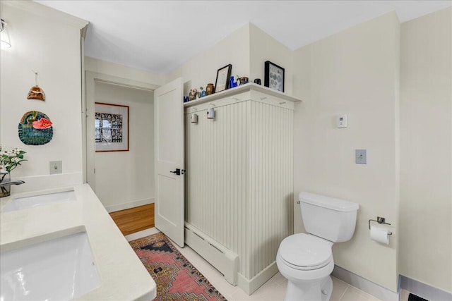 bathroom with double vanity, tile patterned flooring, a sink, baseboards, and toilet