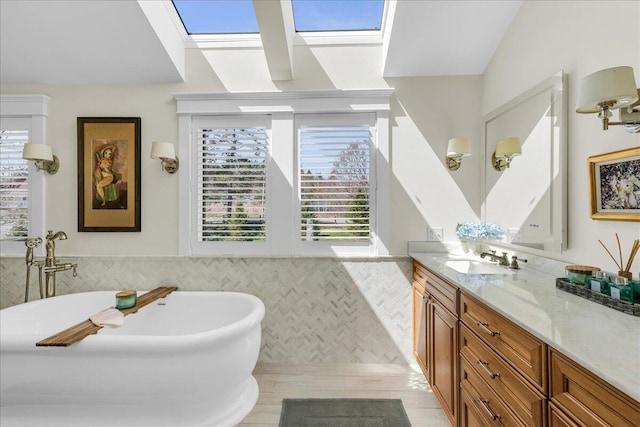 full bath with a healthy amount of sunlight, a freestanding tub, vanity, and tile walls