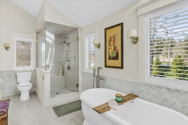 bathroom featuring tile walls, a freestanding bath, vaulted ceiling, and a stall shower