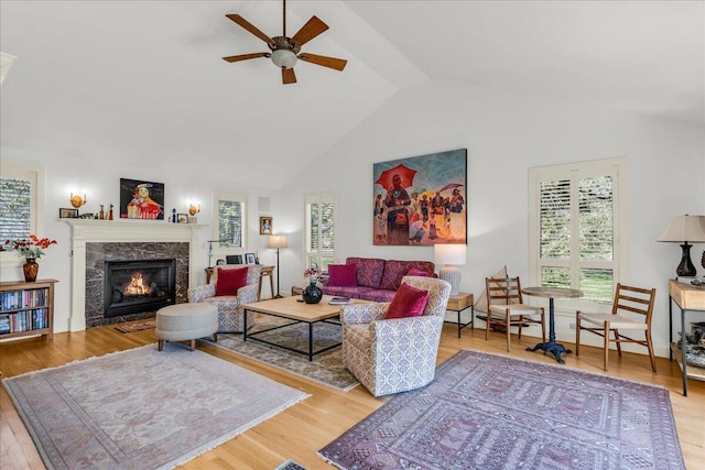 living room featuring ceiling fan, plenty of natural light, and a fireplace