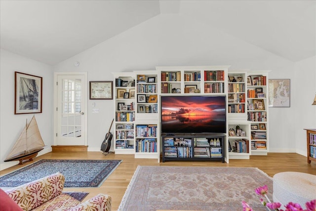 living area featuring baseboards, wood finished floors, and high vaulted ceiling